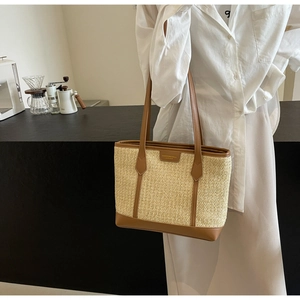Detail showing the straw texture and brown leather strap of the rainbow tote bag