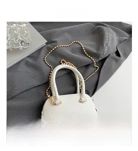 Macro view of white lychee pattern mini shell bag with golden chain and round handle