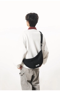 Détail d'un sac besace en nylon noir avec bandoulière réglable et logo tissé