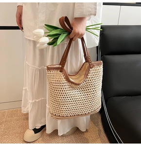 Close-up of woven straw tote bag with brown leather handles and metallic rivets detail