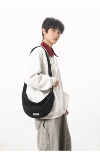 Vue détaillée du sac croissant CHUANGMI en nylon noir avec un écusson logo de marque blanc