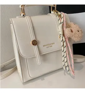 Detail view of cream white PU backpack with metal buckle and plush bear pendant