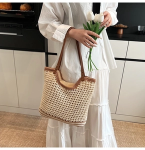 Detail of hand-woven tote bag with leather straps and classic caramel brown trim
