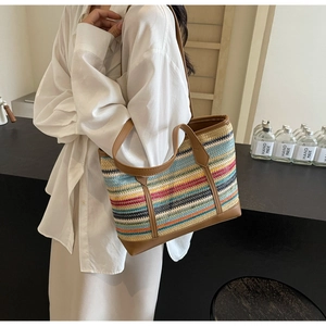 Detail of colorful rainbow woven straw tote bag with brown leather trim and handles