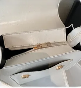 Close-up of white leather handbag with smooth gold zipper and magnetic snap closure