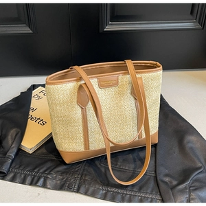 Detail of rainbow straw woven tote bag with brown leather trim and golden logo plate