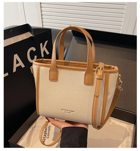 Detail of woven texture tote bag with leather trim and gold-tone hardware accessories