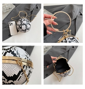 Detail view of spherical snakeskin clutch with gold hardware and rhinestone handle