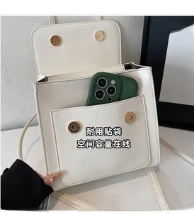 Detail showing the white PU leather square bag front pocket holding a smartphone