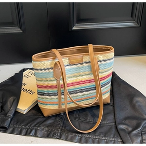 Close-up of rainbow woven tote bag with brown leather trim and metallic brand plaque