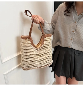 Detail of woven tote bag showing contrasting stitching and brown leather handles
