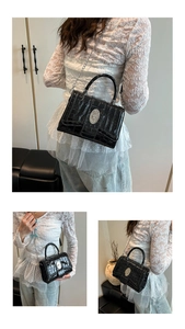 Detail of black crocodile embossed small square bag with silver oval lock buckle