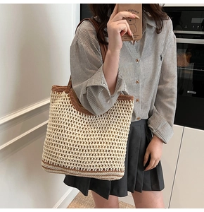 Detail of woven straw tote bag featuring contrast leather straps and grid texture