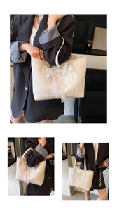 Detail of cream tote bag featuring embossed patterns, lace ribbons, and pearl pendants