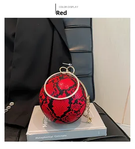 Detail of red snake pattern sphere bag with diamond-set ring handle on a book