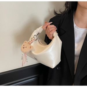 Detail of creamy white pearl finish crescent hobo bag with cute plush bear charm