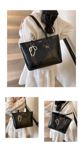 Close-up of black embossed tote bag featuring a pearl bow charm and gold brand tag