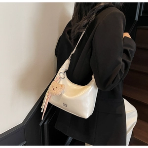 Detail of cream hobo bag with teddy charm and silk scarf on a model outfit