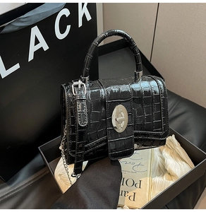Detail of black faux crocodile leather handbag featuring silver metal twist lock and chain