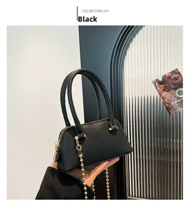 Detail of black lychee grain leather shell bag with gold bead chain strap and top handle