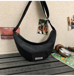 Vue détaillée du sac croissant en nylon noir avec étiquette logo et bandoulière réglable