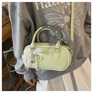 Détail du sac bowling en cuir vert clair avec poignée en foulard et breloque en perles