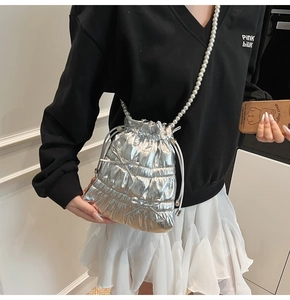 Detail of silver metallic drawstring bucket bag with pearl chain and bow accents