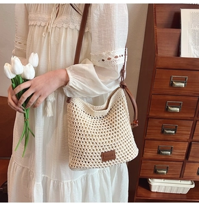 Detailed close-up of cream woven tote bag with brown leather strap and brand logo