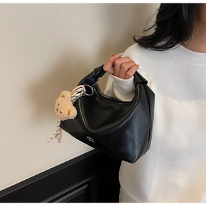 Detail of black matte crescent Hobo bag with plush bear charm and striped ribbon handle