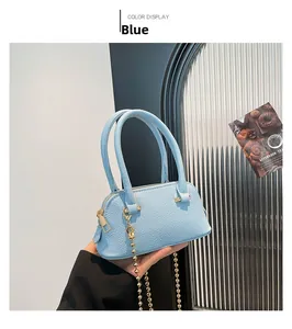 Detail of light blue shell bag with lychee grain texture and gold ball chain strap