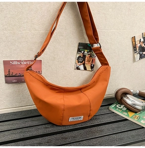 Vue détaillée du sac croissant en nylon orange avec bandoulière réglable et étiquette