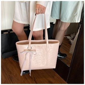 Detail view of pink leather tote bag with embossed pattern and lace pearl charm