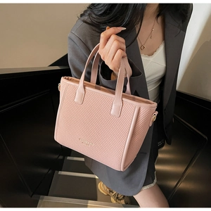 Pink woven bucket bag with smooth leather trim and premium metallic brand logo detail