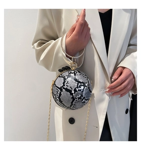 Close-up of snake skin spherical handbag with rhinestone ring handle and gold chain