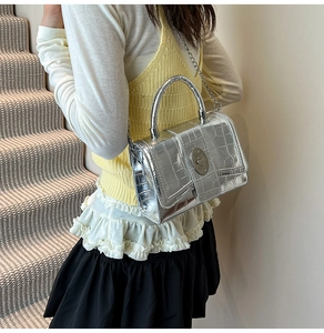 Detail of silver crocodile-embossed mini square bag with metal chain strap and twist lock
