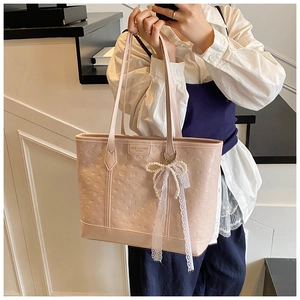 Close-up of pink embossed tote bag featuring heart patterns and pearl lace bow charm