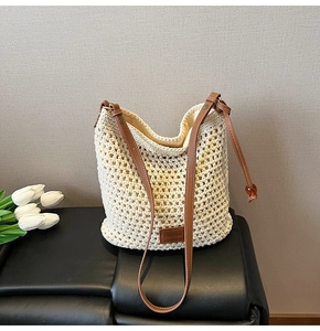 Close-up of woven straw tote bag featuring brown leather logo patch and handle