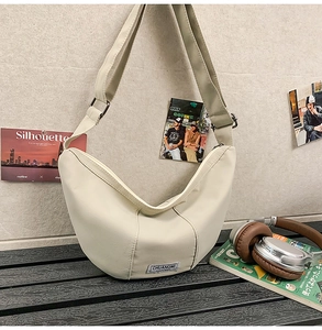 Détail du sac croissant en nylon beige avec étiquette de marque et sangle réglable
