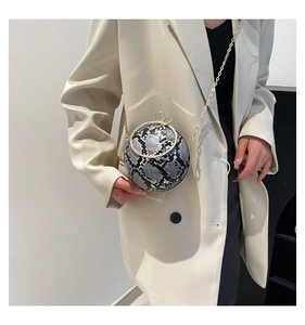 Chic snake-skin spherical evening bag with gold chain strap shown on model shoulder