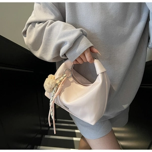 Detail of light pink crescent bag with silver rings, plush bear and striped silk scarf