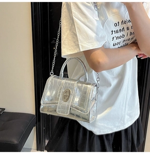 Detail of silver crocodile-textured handbag with metallic clasp and chain strap