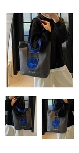 Detail view of large canvas tote bag with contrast blue strap and colorful embroidered text