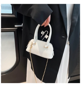 Detail of white mini shell bag with lychee grain texture and golden ball chain strap