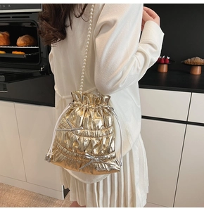 Detail of metallic gold bucket bag with silver bows and large pearl beaded strap