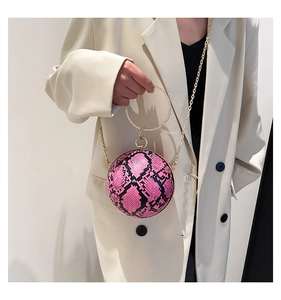 Detailed view of spherical pink snakeskin crossbody bag with golden ring handle and chain