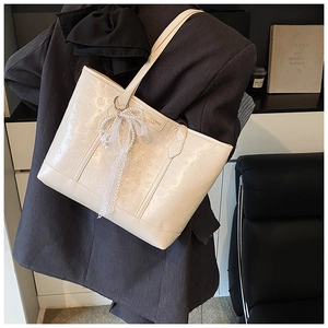Detail of cream white tote bag with embossed cartoon symbols and lace pearl charm