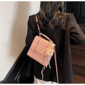 Pink faux leather backpack detail featuring a cute brown plush bear charm and metal buckle