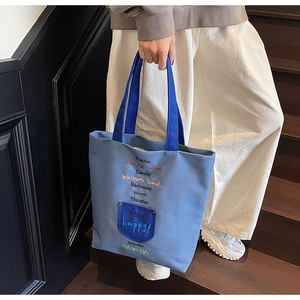 Detail of blue canvas tote bag with colorful embroidery on wooden staircase