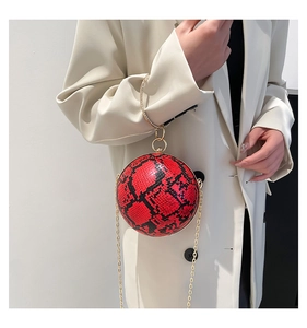 Detailed shot of spherical evening bag with red snake skin texture and gold diamond handle