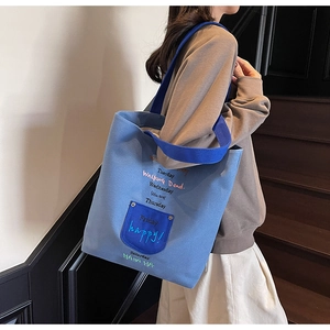 Detail of blue denim canvas tote bag featuring white embroidered weekly mood typography